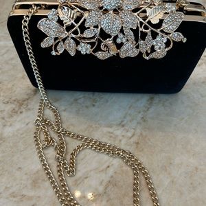 Women’s evening clutch, black and gold with floral rhinestone closure.